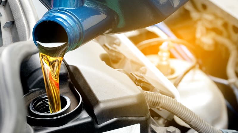 Öl lauft aus einem Kanister in einen Automotor