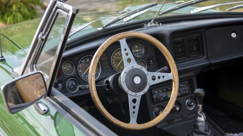 Blick in ein grünes Oldtimer Cabrio mit einem hölzernen Lenkrad