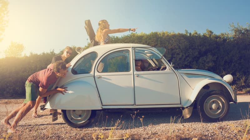 Jugendliche schieben einen alten, weißen VW Käfer