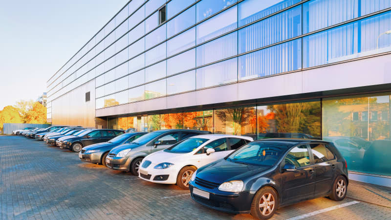 Autos auf einem Mitarbeiterparkplatz vor einem Bürogebäude