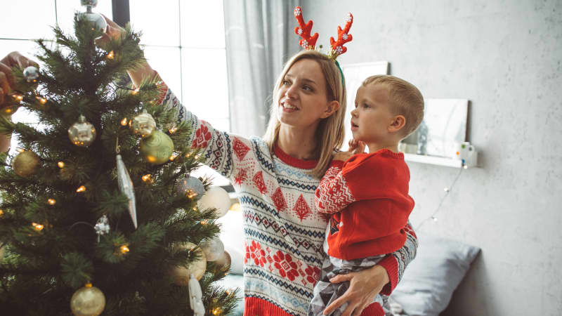 Frau schmückt mit ihrem Sohne den Weihnachtsbaum