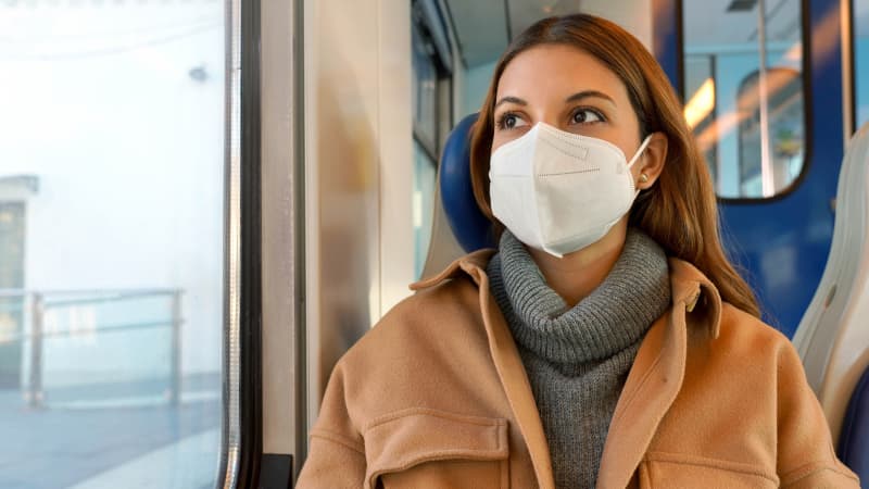 Frau sitzt mit FFP2 Maske im Zug