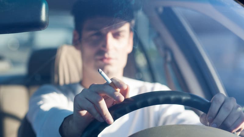Mann fährt Auto mit Zigarette in der Hand