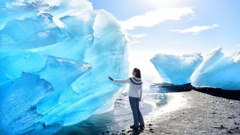 Frau steht an Eisberg in Island