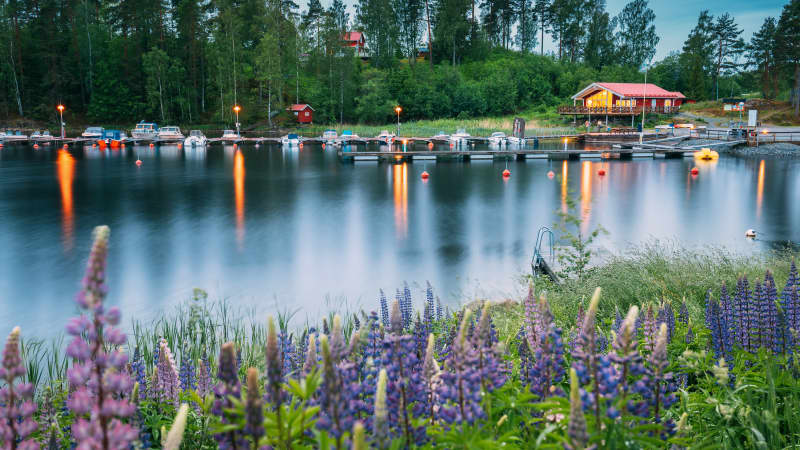 Schöne rote schwedische Holzhütte Haus und Pier in der Nähe von See in Sommer Abend