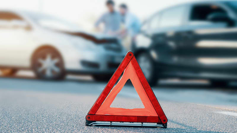 Warndreieck steht vor zwei Autos nach einem Unfall