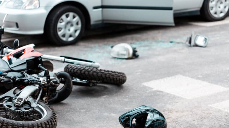 Motorrad und Helm liegen nach einem Unfall mit einem Auto auf der Straße