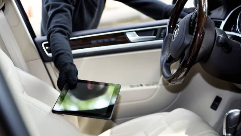 Schwarzgekleideter Dieb klaut Tablet durch ein Autofenster