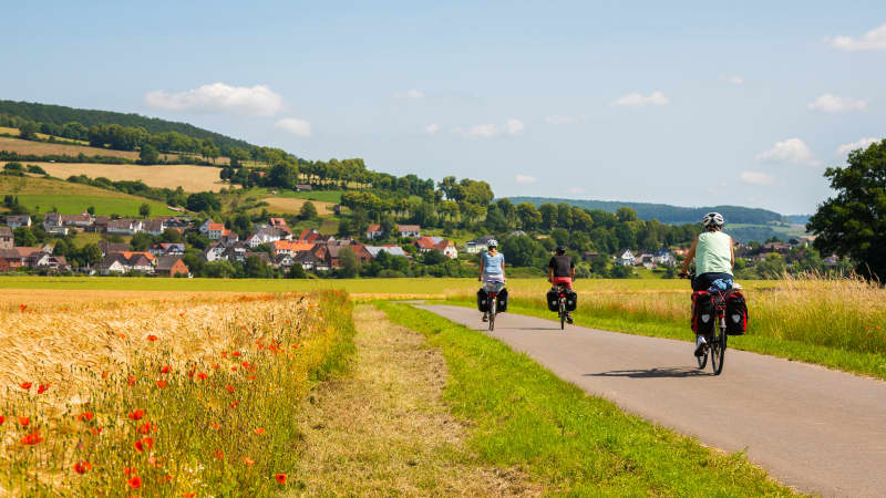 Fahrradfahrer fahren auf einem Radweg durch Felder