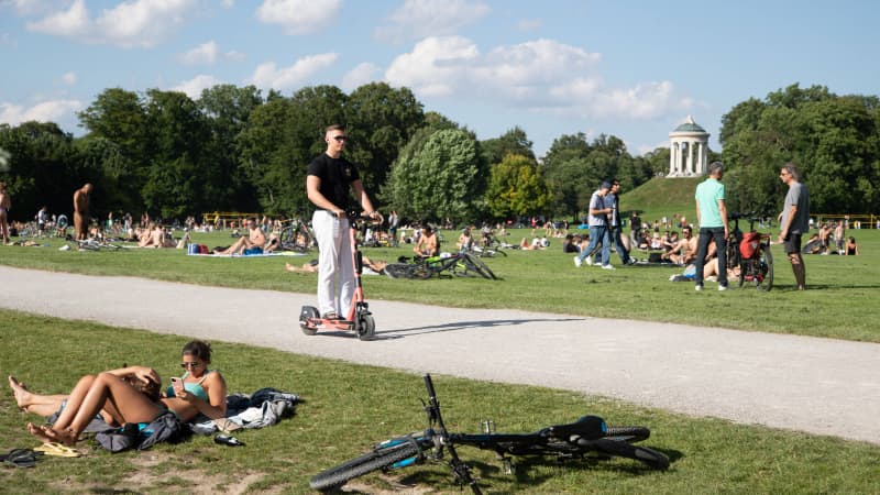 Ein junger Mann fährt auf einem E-Scooter im englischen Garten in München