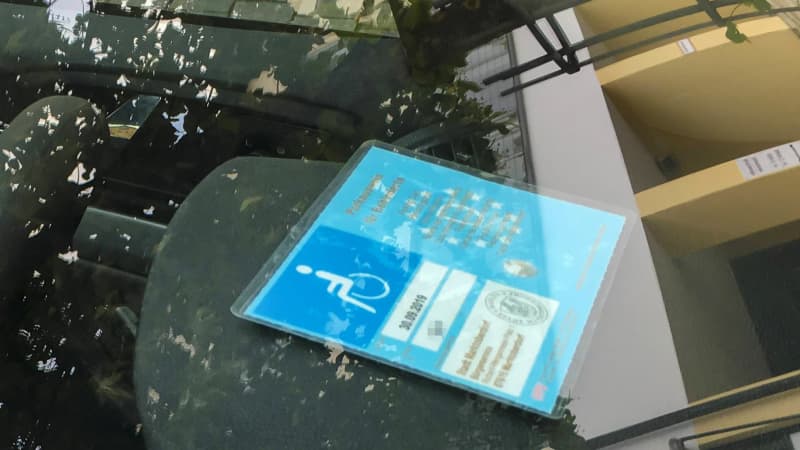 Ein Behinderten-Ausweis liegt in einem Auto vorne an der Windschutzscheibe