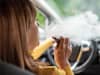 Eine Frau raucht am Steuer ihres Autos eine E-Zigarette