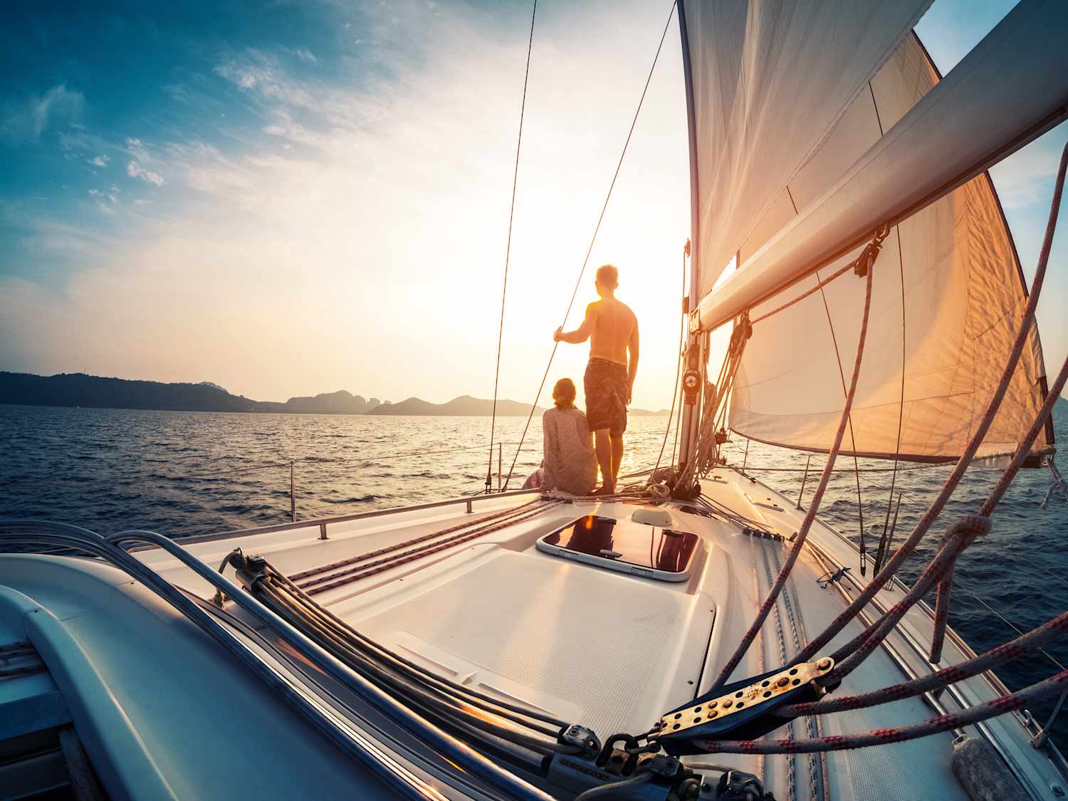 Mann und Frau stehen am Bug eines Segelschiffs