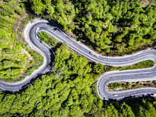 Autos fahren auf einer kurvigen Strasse von oben fotografiert