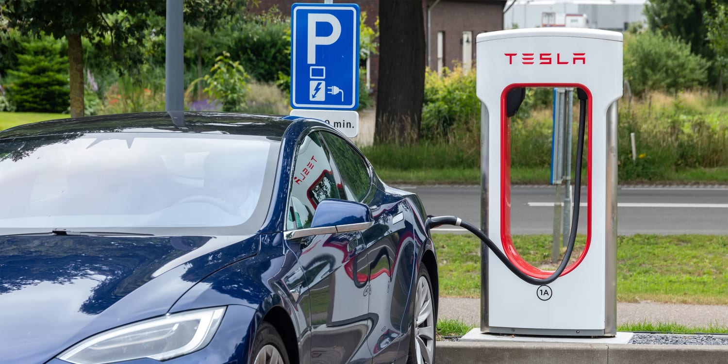 Eine tesla-ladestation mit einem grünen auto im hintergrund