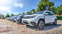 Verschiedene Dacia Modelle stehen auf dem Kiesparkplatz bei einem Autohändler im Sommer
