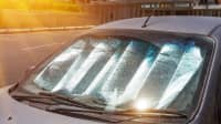 Reflektierende Folie als Hitzeschutz hinter der Windschutzscheibe eines grauen PKWs