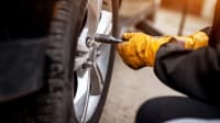 Mensch zieht Schrauben bei einem Autoreifen fest