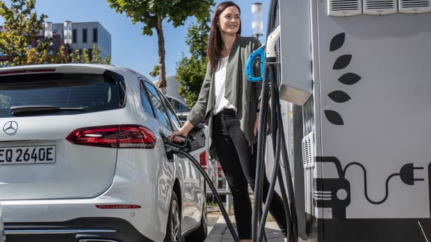 Eine Fau tankt ihr Elektroauto an einer Ladesäule auf