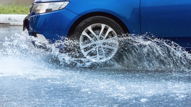 Ein Auto fährt durch eine tiefe Pfütze und das Wasser spritzt.