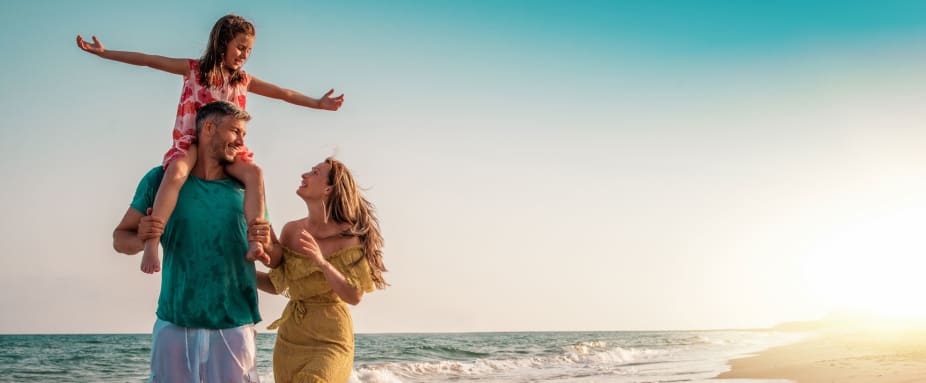 Paar mit ihrer Tochter am Strand: Auslandskrankenversicherung für Familien