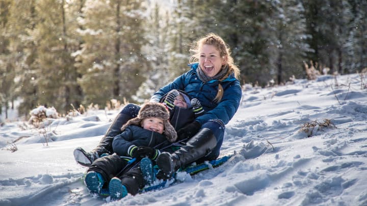 Mutte rund Kind fahren Schlitten - Auslandskrankenversicherung für Wintersportler ADAC