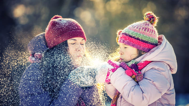 Mutter und Kind pusten sich Schnee ins Gesicht - Rechtsschutzversicherung für Wintersportler