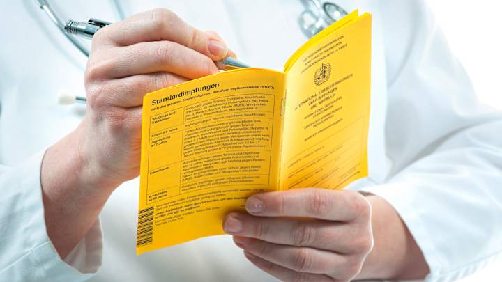 Ein Arzt trägt eine Impfung in ein Impfbuch ein