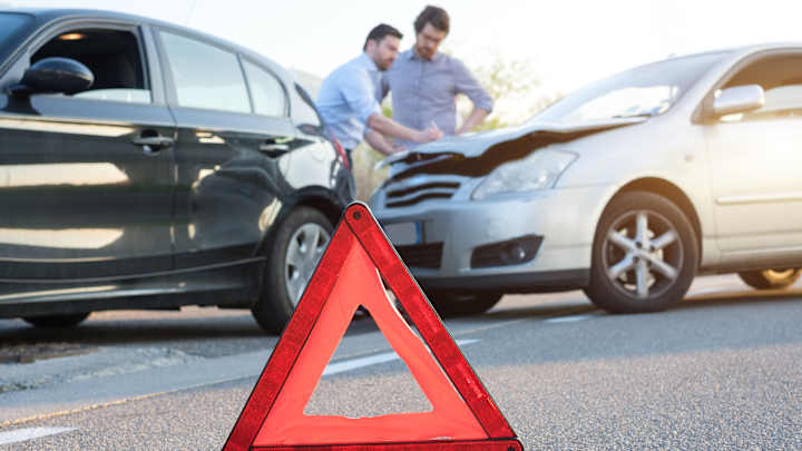 2 Männer stehen nach ienem Unfall zusammen und füllen den Unfallbericht aus