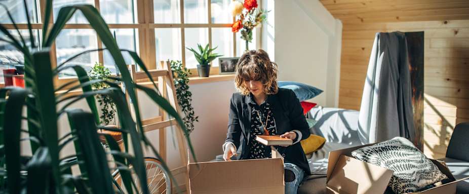 Junge Frau zieht während der Coronakrise in einen neue Wohnung um und packt Kisten aus