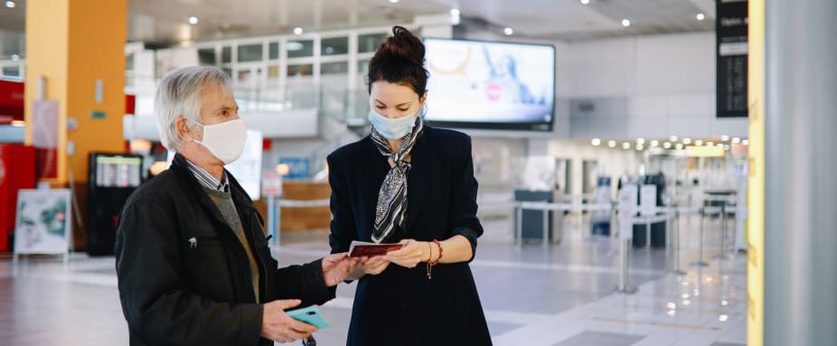 Eine Frau kontrolliert den Reiseausweis eines Mannes  am Flugahfen