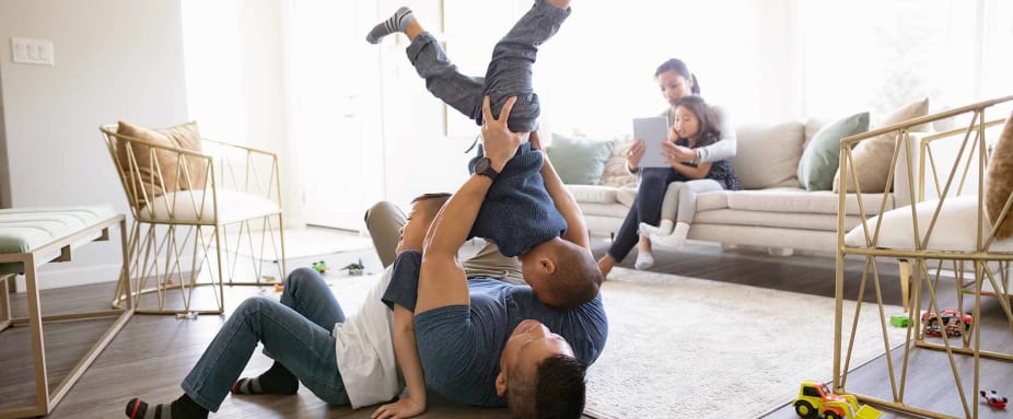Familie spielt im Wohnzimmer - Unfallversicherung ADAC