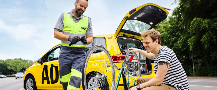 ADAC Pannenhelfer hilft einem Radfahrer mit seinem kaputten Fahrrad
