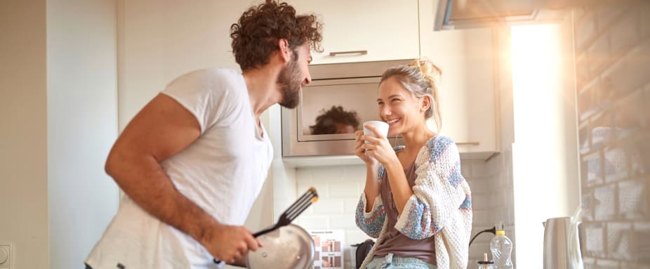 Lachendes Paar in der gemeinsamen Küche: Hausratversicherung
