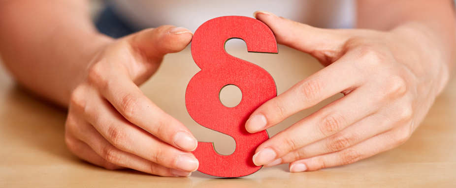 Zwei Frauenhände halten rotes Paragrafenzeichen - Was ist eine Rechtsschutzversicherung