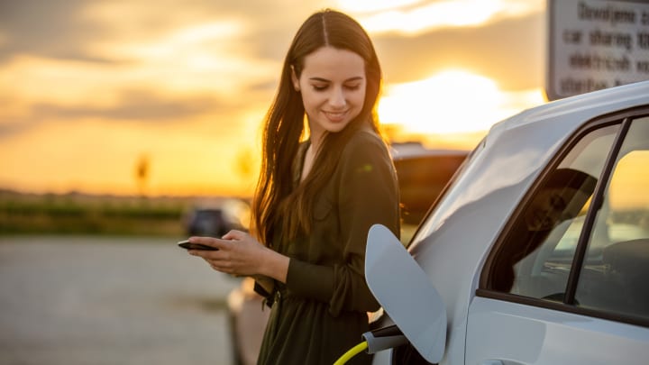 Frau lädt eine Elektroauto - Elektroauto-Versicherung