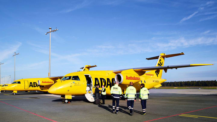 ADAC Ambulanzflotte steht auf Startfeld, ein Ärzteteam geht vor den Fliegern
