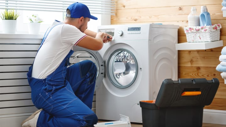 Handwerker repariert eine Waschmaschine - Reparatur Haushaltsgroßgeräte