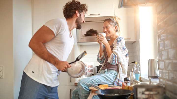 Lachendes Paar in der gemeinsamen Küche: Hausratversicherung