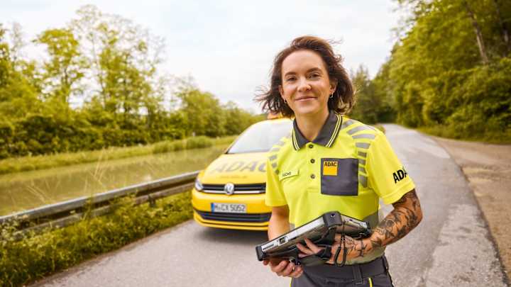 Strassenwachtfahrerin lächt, im Hintergrund ist ein ADAC Auto