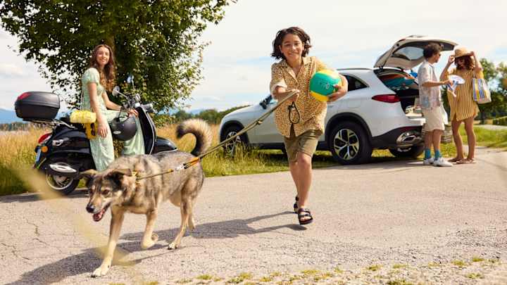 Familie mit Kinder und Hund st mit Auto und Roller am Badesee angekommen