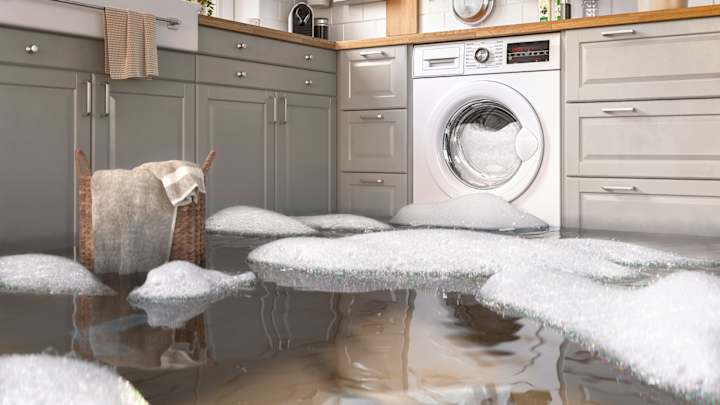 Waschmaschine in der Küche ist ausgelaufen, Wasser und Schaum auf dem Boden