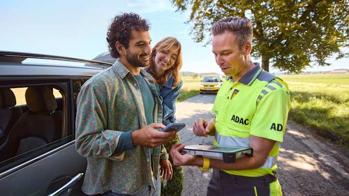 Der ADAC Strassenwachtfahrer hilft einem Paar bei einer Autopanne