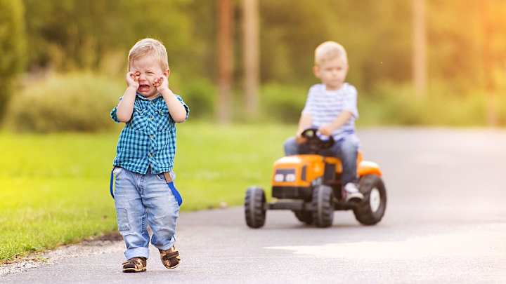 Ein Junge fährt auf Spielzeug-Traktor, ein Junge weint - Verkehrs-Rechtsschutz ADAC