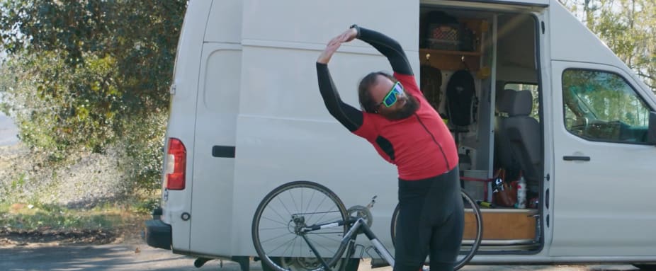 Fahrradfahrer, der sich vor seinem Wohnmobil streckt