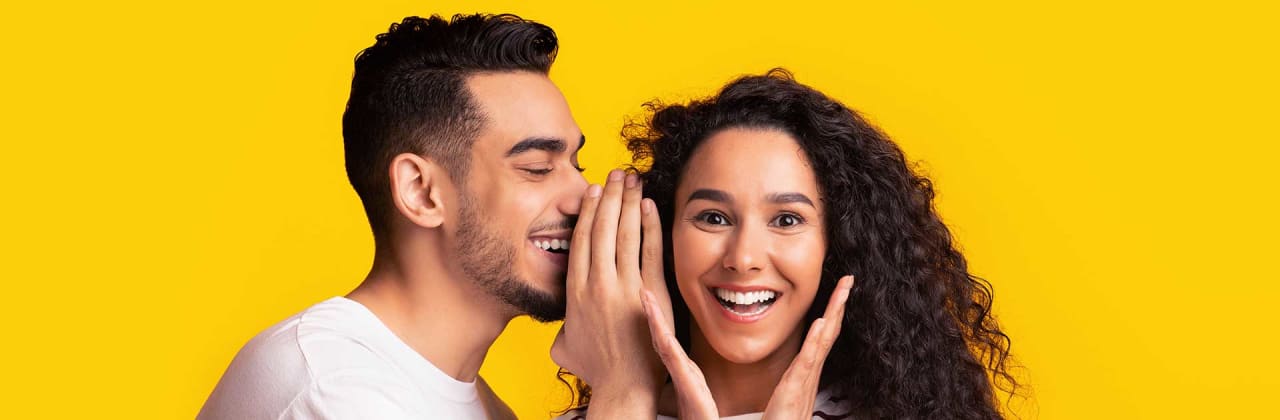 Mann flüstert Frau etwas zu - Versicherungen empfehlen ADAC