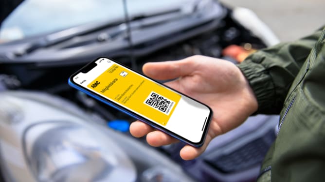 Mann schaut bei einer Panne auf die Mitgliedskarte in seinem Smartphone - ADAC Mitgliedskarte
