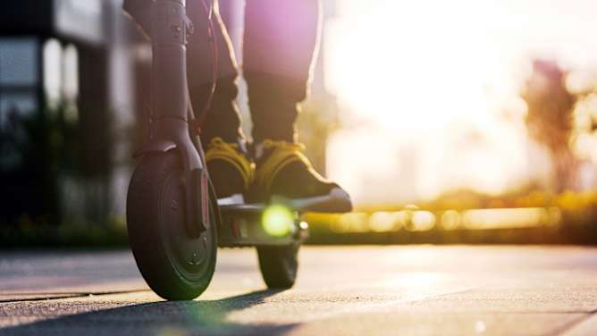 Füße eines Mannes auf einem E-Scooter