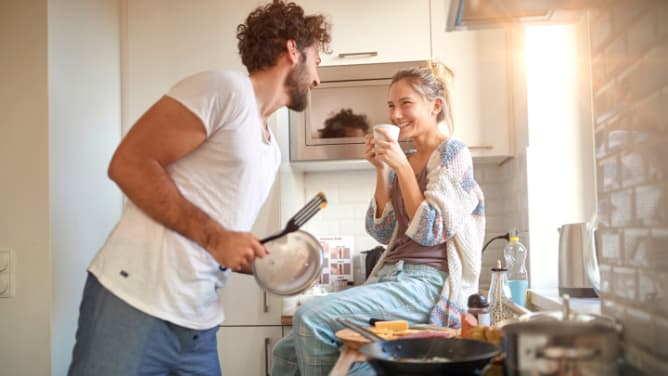 Lachendes Paar in der gemeinsamen Küche: Hausratversicherung