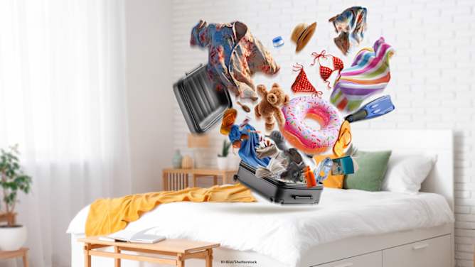 Platzender Urlaubskoffer steht auf einem Bett in einem Schlafzimmer, Sachen fallen heraus